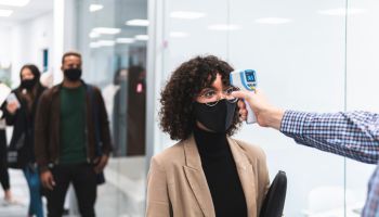 Female professional goes through temperature check before going to work in office