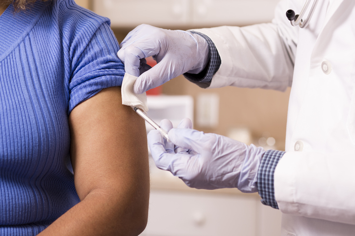 Active senior male doctor administers vaccination to young adult.