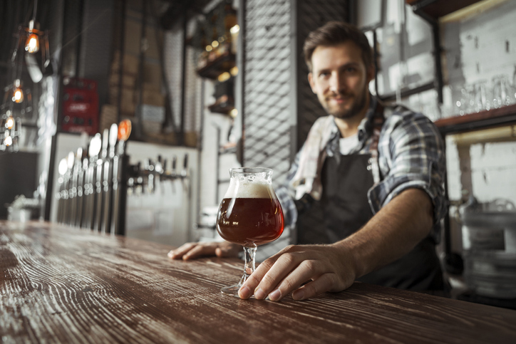 Bartender looking in camera serving beer