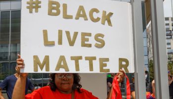 Black Lives Matter advocate holds a placard that says #...