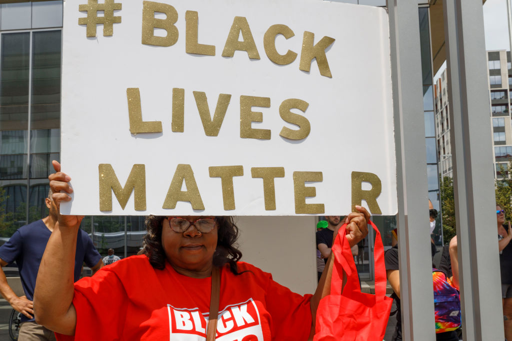 Black Lives Matter advocate holds a placard that says #...