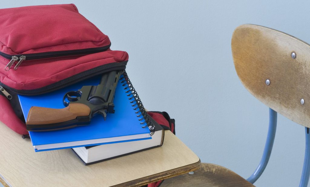 Backpack with book, notebook, and handgun on desk