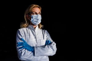 Female doctor with protective face mask and gloves with arms crossed