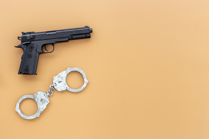 Hand gun weapon with handcuffs - illegal use of weapons concept