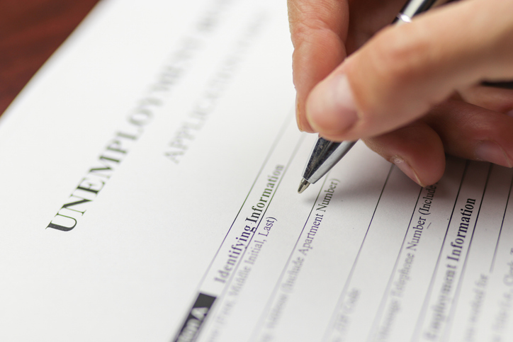 Close-up of a person's hand filing social security benefits application form.