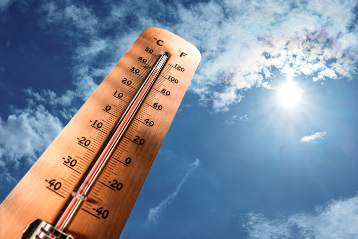 Thermometer showing tropical heat and sky with hot sun rays in Celsius and Fahrenheit.