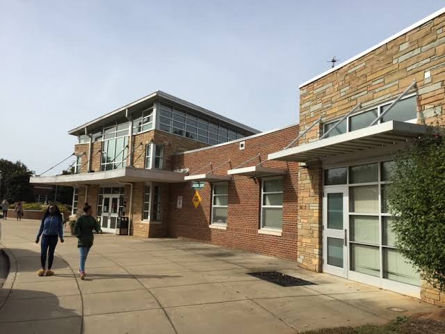A brick and glass building with a covered walkway and people walking outside.
